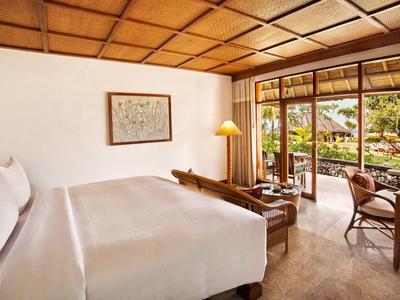 Lichte hotelkamer met groot bed en toegang tot terras met uitzicht op de tuin.