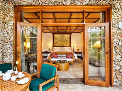 Open glazen deuren leiden naar een gezellige hotelkamer met houten muren en een terras met zithoek.