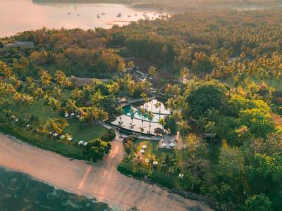 Luftaufnahme eines Resorts am Strand, umgeben von dichtem grünem Wald.