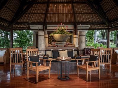 Offener Lounge-Bereich mit Holzmöbeln und Kamin in einem tropischen Hotel.