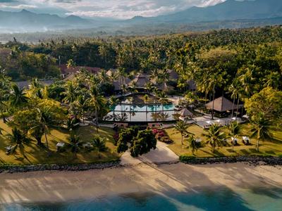 Een tropisch resort met zwembad, palmbomen en strand voor bergen.
