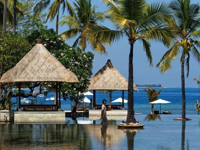 Pavillons und Palmen am Wasser mit Blick auf das Meer an einem sonnigen Tag