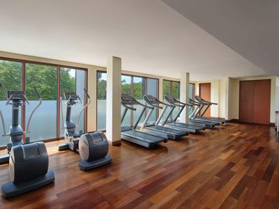 Palestra con attrezzature moderne e grandi finestre con vista sugli alberi.
