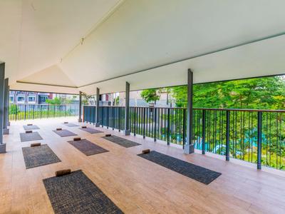 Area esterna coperta con tappetini da yoga che si affaccia su una piscina vicina e un ambiente verde.