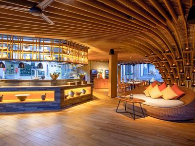 Bar dell'hotel moderna con soffitto in legno, zona salotto accogliente e illuminazione ambientale.