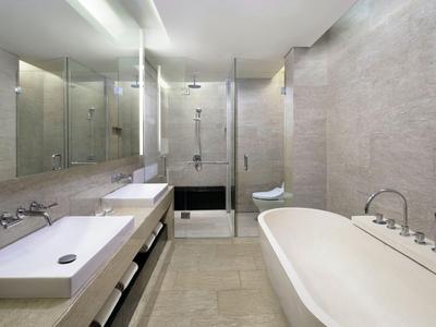 Bagno moderno con vasca autoportante e ampia doccia in vetro in una camera d'hotel.