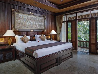 Gemütliches Hotelzimmer mit großem Bett, Holzmöbeln und Blick auf einen grünen Garten.
