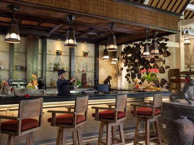 Elegante Hotelbar mit Holzmöbeln, warmem Licht und dekorativem Hintergrundelement.
