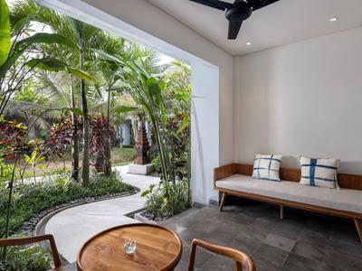Moderner Lounge-Bereich mit Sofa und Blick auf tropischen Garten durch große Öffnung.