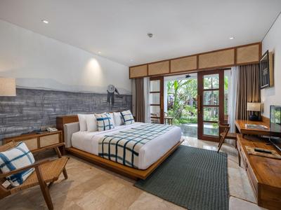 Helles Hotelzimmer mit großem Bett, Holzmöbeln und Blick auf einen Garten.