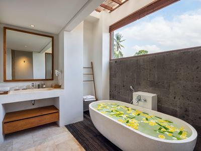 Modernes Badezimmer mit freistehender Badewanne und Blumendekor neben Waschbecken und Spiegel.