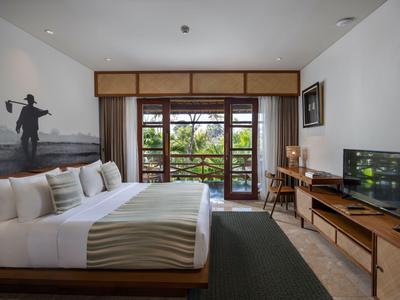 Modernes Hotelzimmer mit großem Bett, Balkon und Blick auf grünes Umfeld.