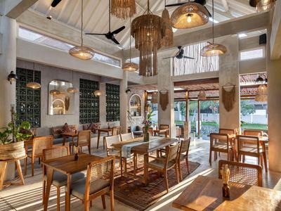 Helles Restaurant mit Holzmöbeln, Hängelampen und großen Fenstern in einem Hotel.
