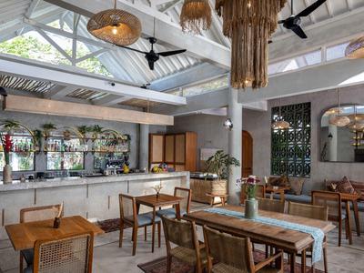 Helle Hotellobby mit Holzstühlen, Tischen, großen Fenstern und modernem Dekor.