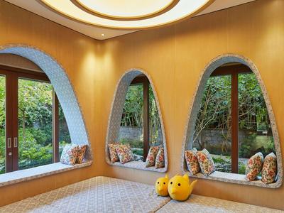 Gemütliche Ecke mit dreifachen bogenförmigen Fenstern und weichen Kissen in einem Hotel-Relaxraum.