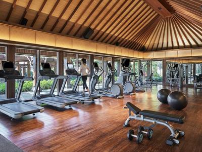 Moderner Fitnessraum mit Holzboden, mehreren Laufbändern und Fitnessgeräten in einem Hotel.