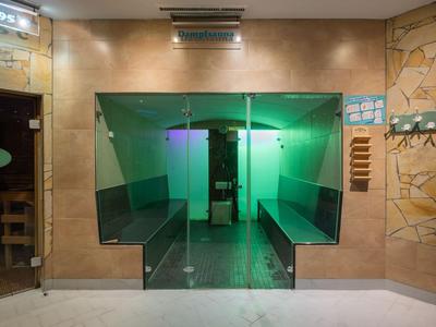 Moderner Wellnessbereich mit Sauna und Sitzen, Glasfront und sanfter Beleuchtung.
