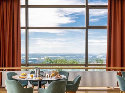 Hotel-Frühstückstisch mit Croissants vor großen Fenstern mit Landschaftsblick.