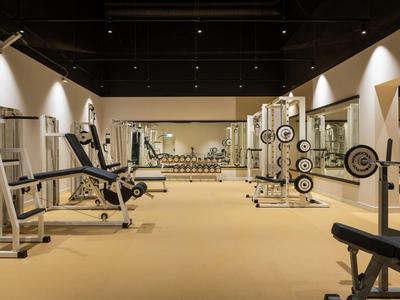 Ein moderner Fitnessraum mit verschiedenen Trainingsgeräten und Hanteln in einem Hotel.