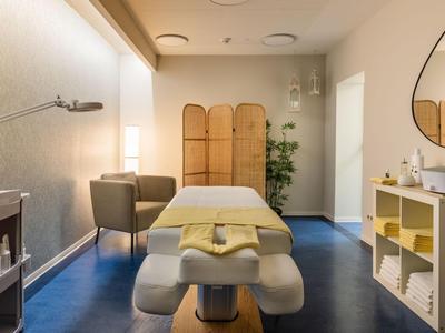Helles Wellnesszimmer mit Massageliege, Handtüchern und entspannter Atmosphäre.