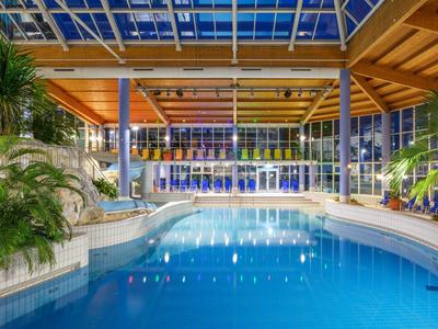 Moderner Innenpool mit großen Fenstern und Holzdecke in Hotelatmosphäre.