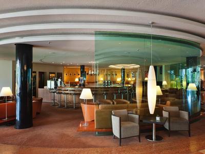 Moderner Hotel-Loungebereich mit runden Sitzen, Lampen und einer runden Bar.