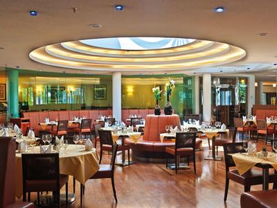 Helles, modernes Restaurant mit runden Deckenfenster und elegant gedeckten Tischen.