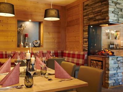 Gemütlicher Essbereich mit Holzwänden, Kamin und gedecktem Tisch mit Servietten und Wein.