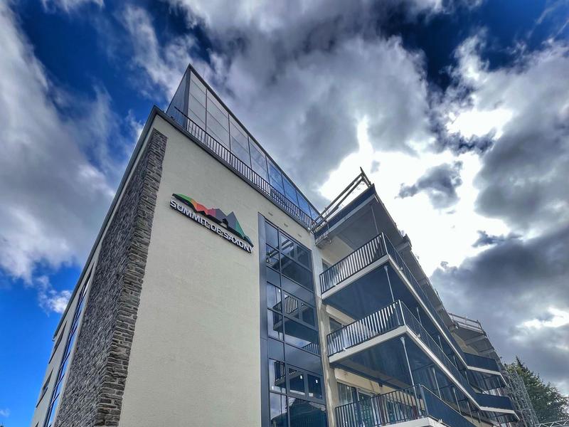 Torre dell'hotel moderna su più piani con balconi in vetro sotto un cielo nuvoloso.