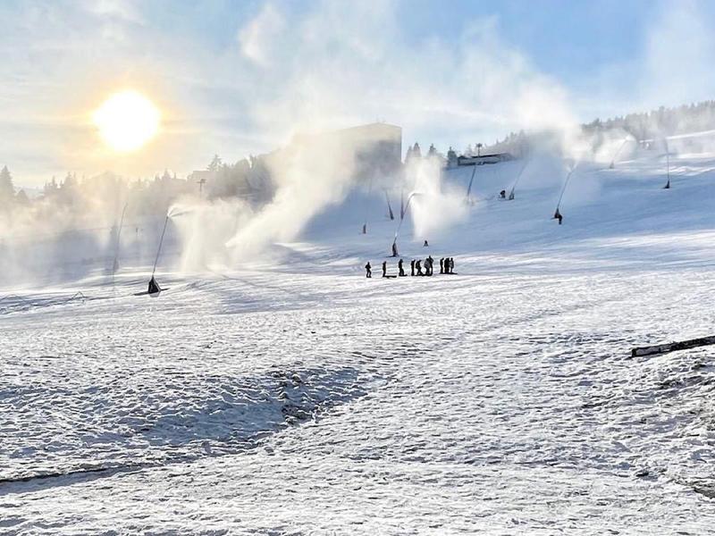 Paesaggio innevato con sciatori e luce solare in un cielo nuvoloso.