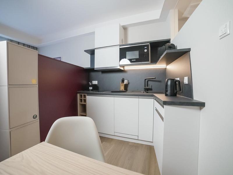 Angolo cottura moderno con mobili bianchi, microonde e bollitore in una camera d'hotel.