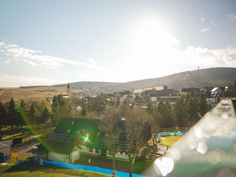 Paesaggio soleggiato con colline, case e alberi sotto un cielo limpido