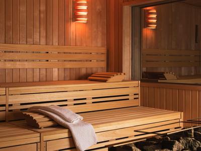 Holzsauna mit zwei Etagen, warmem Licht, Handtuch und Rückenlehne auf der unteren Bank.