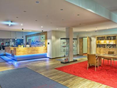 Moderner Hotel-Lobbybereich mit Rezeption, Sitzbereich und hellem Holzfußboden.