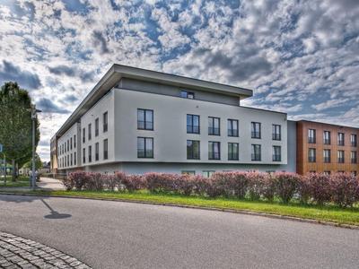 Modernes Gebäude mit bepflanztem Vorgarten unter bewölktem Himmel