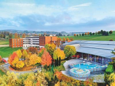 Hotelgebäude mit herbstlich bunten Bäumen und Schwimmbad im Außenbereich in ländlicher Umgebung