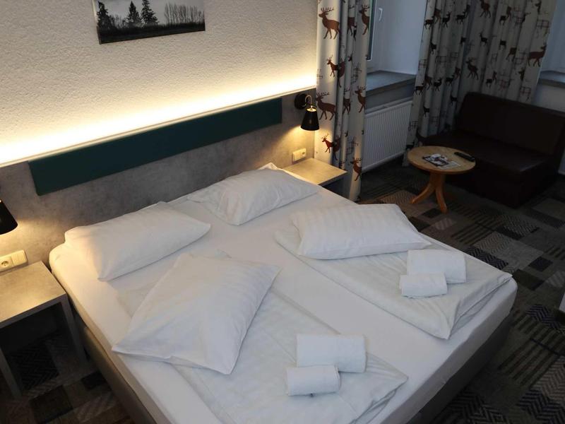 Moderně zařízený hotelový pokoj s manželskou postelí a čistými ručníky.