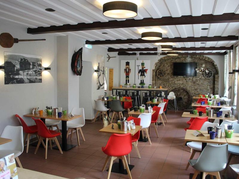 Příjemná restaurace s barevnými židlemi a rustikálním krbem v pozadí.