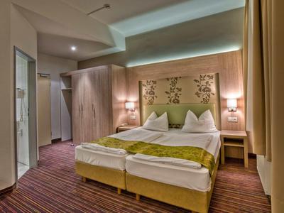 Modern eingerichtetes Hotelzimmer mit Doppelbett, Holzmöbeln und weicher Beleuchtung.