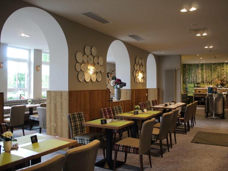 Gemütliches Restaurant mit Holztischen, gepolsterten Stühlen und runden Wandspiegeln.