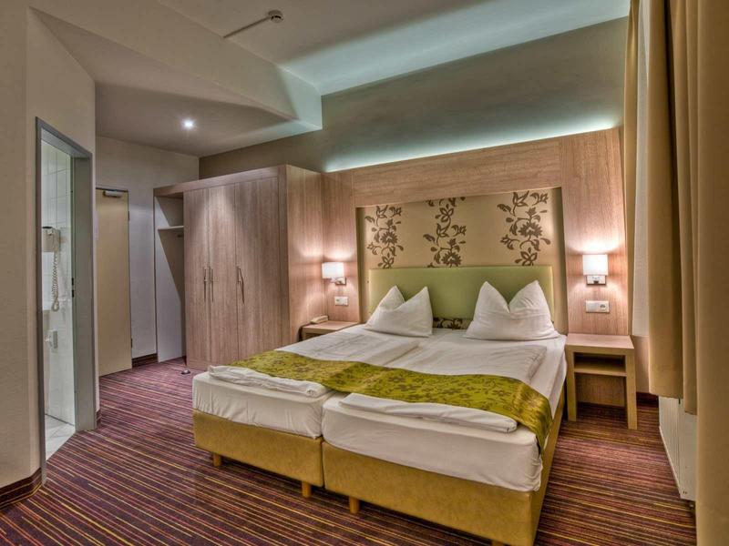 Modern eingerichtetes Hotelzimmer mit Doppelbett, Holzmöbeln und weicher Beleuchtung.