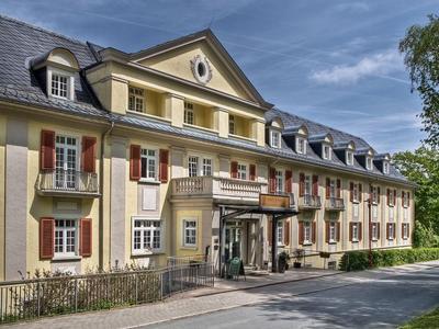 Großes historisches Hotelgebäude mit gelber Fassade und Mansardendach unter blauem Himmel.