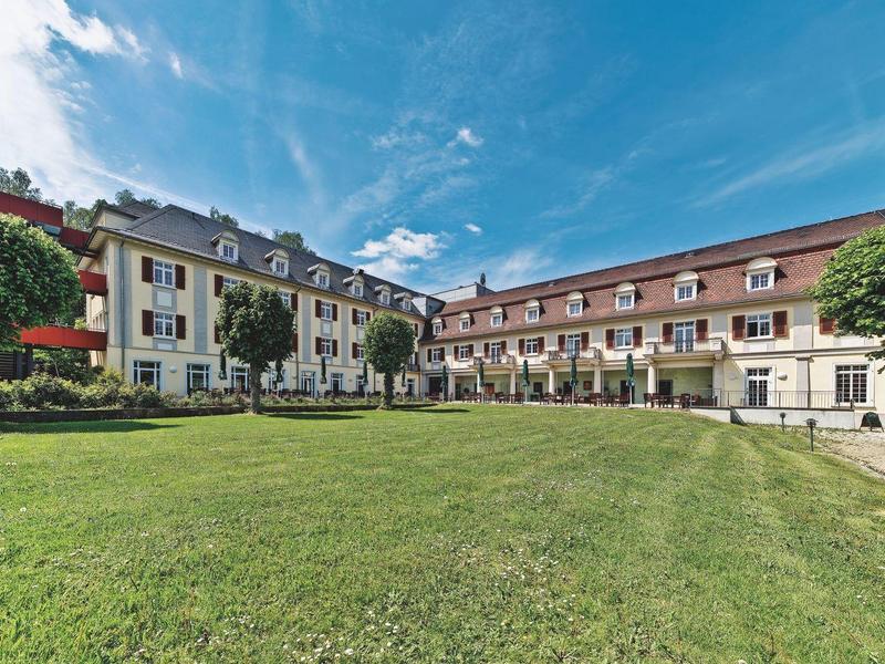 Large hotel building with expansive green lawn and blue sky.
