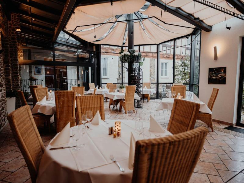 Elegant restaurant with set tables, wicker chairs, and large glass wall.
