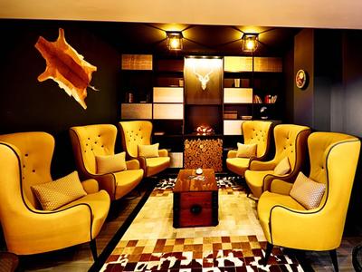 Gemütlicher Raum mit gelben Sesseln um einen Tisch und warmen Lichtquellen.