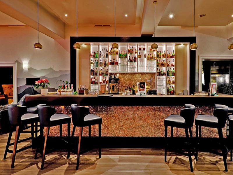 Moderní hotelový bar s elegantním osvětlením a vysokými židlemi