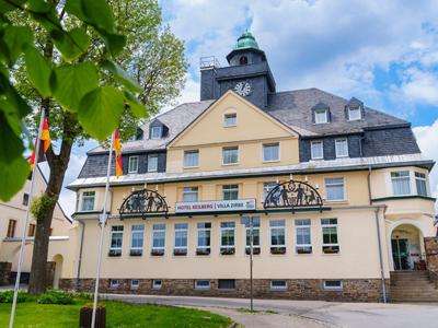 Historisches gelbes Gebäude mit schwarzem Schieferdach und Turm unter blauem Himmel