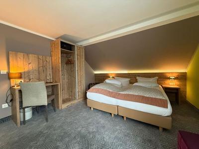 Gemütliches Hotelzimmer mit Doppelbett, Schreibtisch, Stuhl und indirekter Beleuchtung.