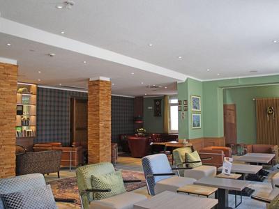 Modern eingerichteter Hotel-Loungebereich mit Tischen, Stühlen und gemütlichen Sitzmöglichkeiten.
