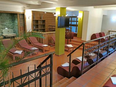 Innenansicht eines Hotels mit Sitzbereich, Loungemöbeln und Fernseher an der Wand.